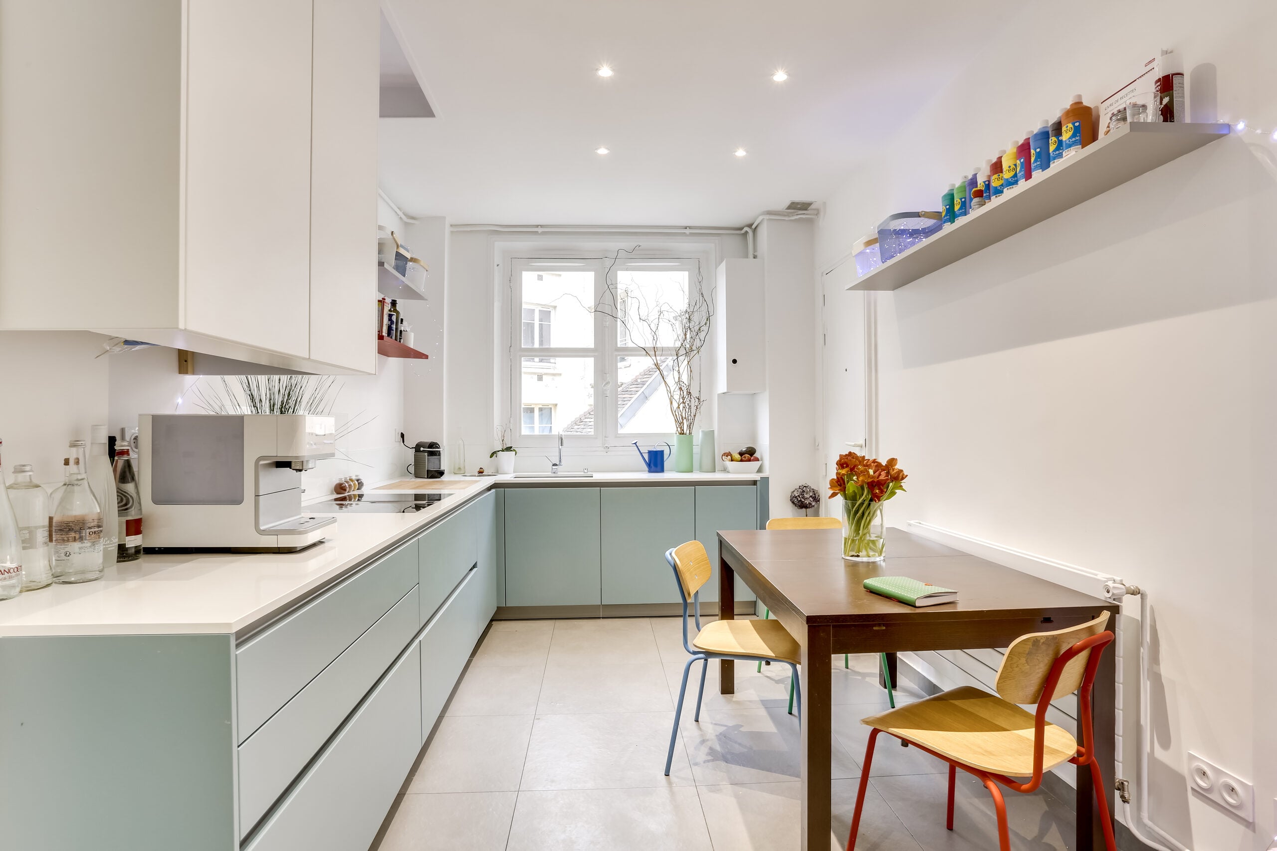 Cuisine avec armoires bleu canard, comptoirs blancs et table en bois