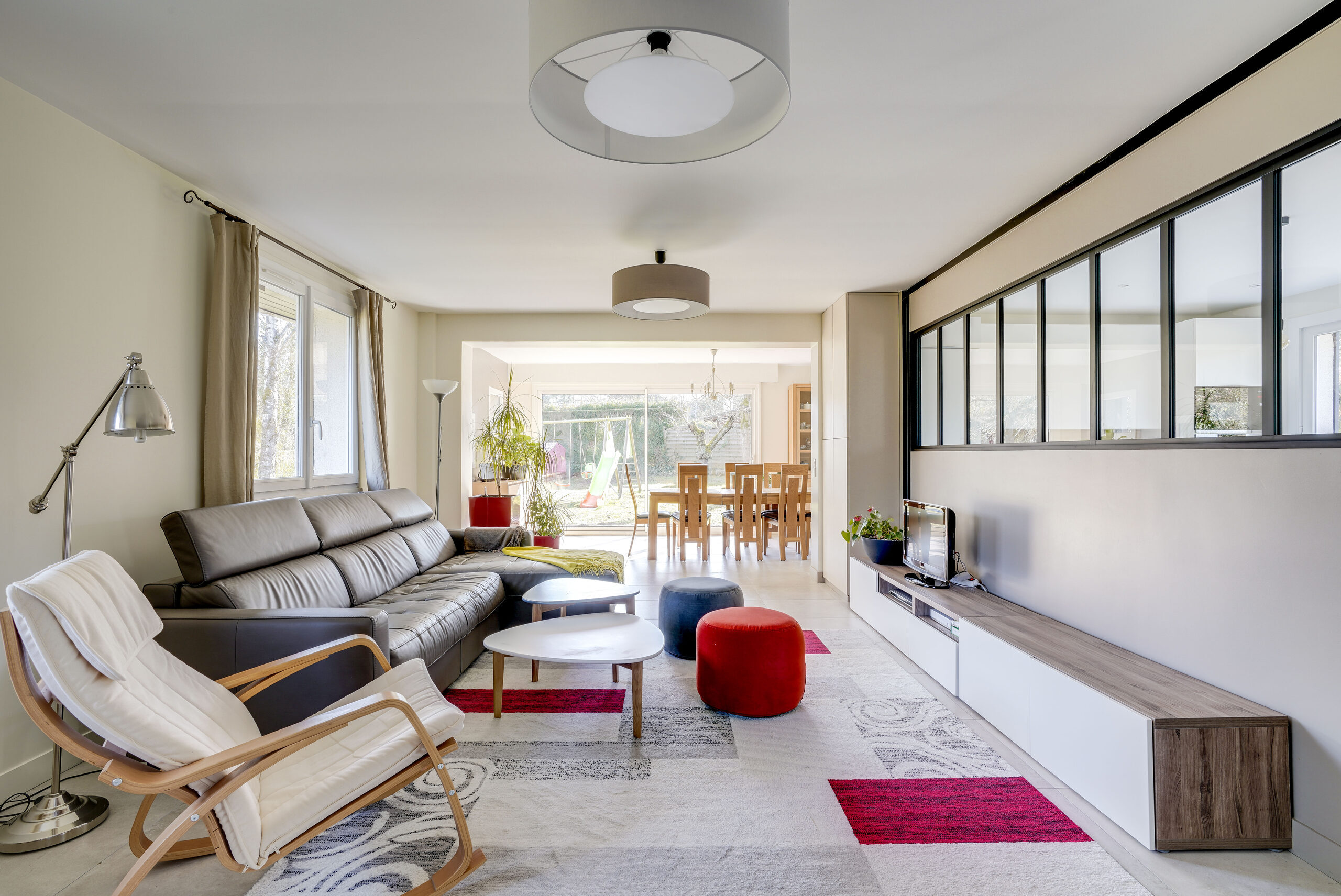 Salon contemporain avec canapé en cuir anthracite et verrière noire, réalisation Dec Home