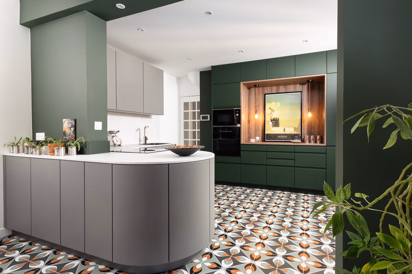 Cuisine aux armoires vert émeraude et grises sur carrelage à motifs géométriques avec four encastré