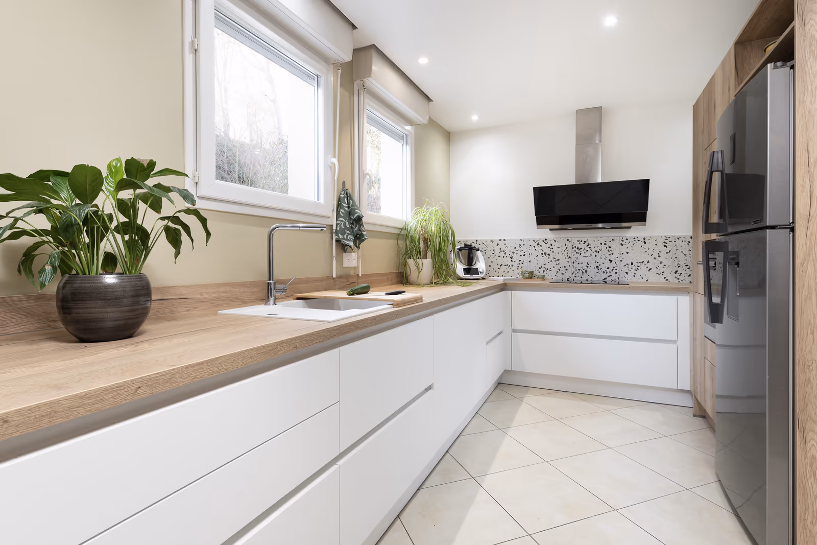 Cuisine longue blanche avec comptoirs en bois et hotte en inox