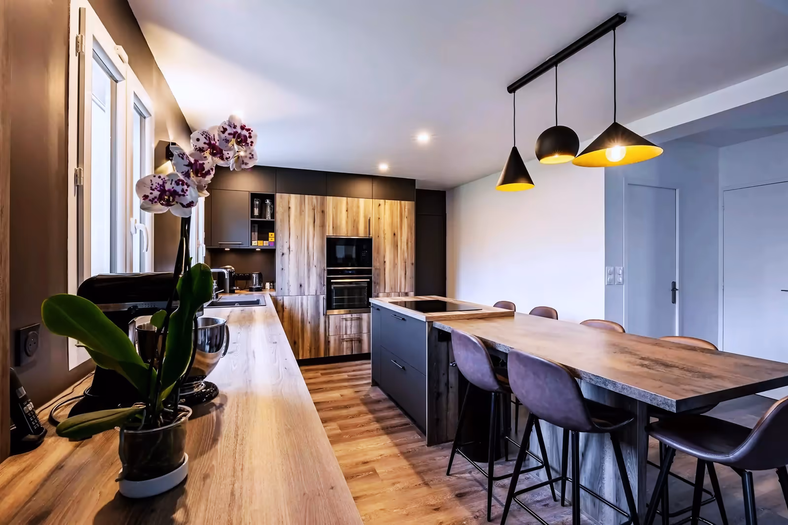 Cuisine nordique avec comptoirs en bois, îlot central, tabourets et fours encastrés