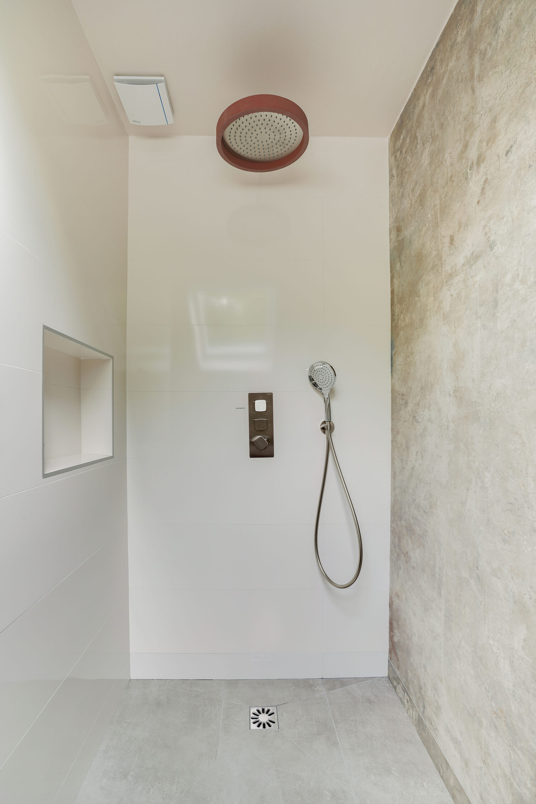Douche à l'italienne Baxar avec pommeau de pluie, parois en béton ciré, niche murale encastrée et receveur extra-plat, réalisation Dec Home